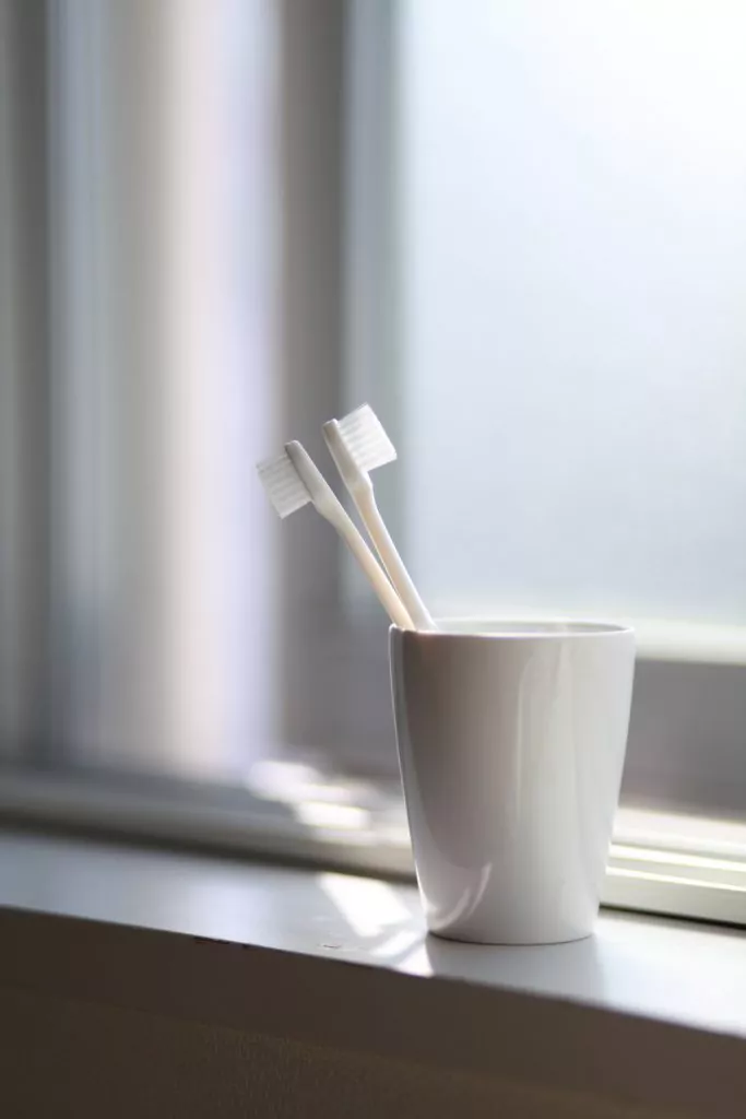 Toothbrush in cup next to a window